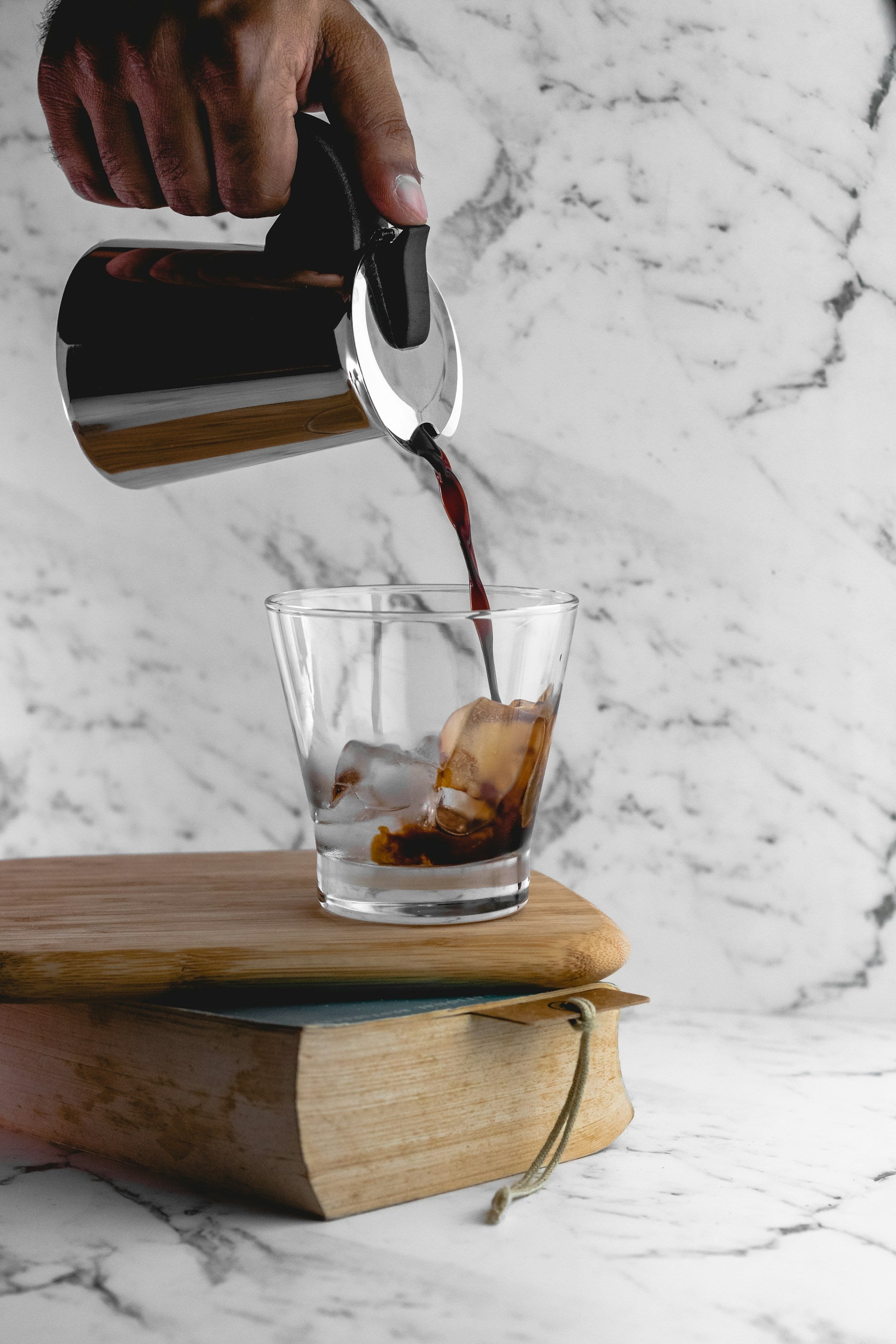 Specialty coffee being brewed in a Chemex coffee maker sitting on counter next to two glasses and a silver kettle.